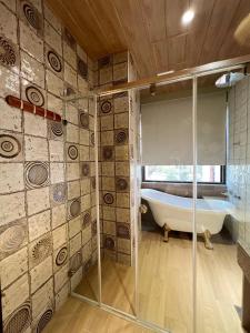 un bagno con vasca e doccia in vetro di Shange Beach Club Homeatay a Città Vecchia di Hengchun