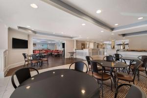 a dining room with tables and chairs and a kitchen at SureStay Plus Hotel by Best Western Plano in Plano