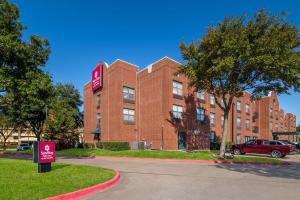 a red brick building with a sign in front of it at SureStay Plus Hotel by Best Western Plano in Plano