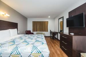 a hotel room with a bed and a flat screen tv at Studio 6 Channelview TX Baytown West in Channelview