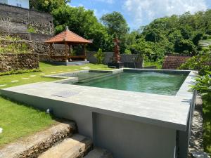 une piscine dans un jardin avec un kiosque dans l'établissement Belong Bunter Homestay, à Uluwatu