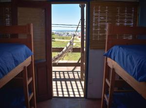 a room with two bunk beds and a door to a porch at Mar de Fondo Hostel in Punta Del Diablo