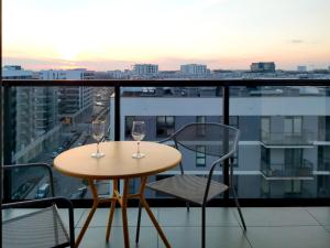 a table with two wine glasses on a balcony at Apartament 9, z oddzielną sypialnią! in Warsaw