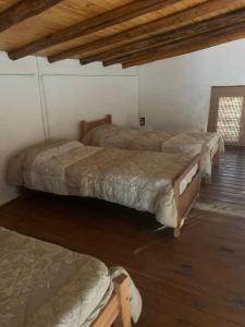 3 camas en una habitación con suelo de madera en los Reyunos Club Náutico y Pesca - TiloHouse en San Rafael