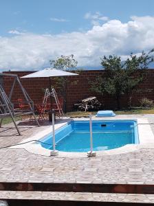 een zwembad met een parasol naast een bakstenen muur bij Cabañas Mundo al revés in La Silleta