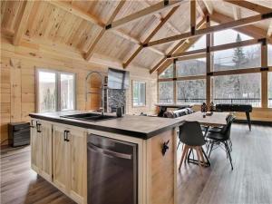 a kitchen and living room in a log cabin at Chalet l'amical avec Spa in Saint-Philémon