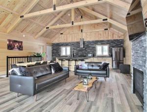 a living room with leather furniture and a fireplace at Chalet l'amical avec Spa in Saint-Philémon