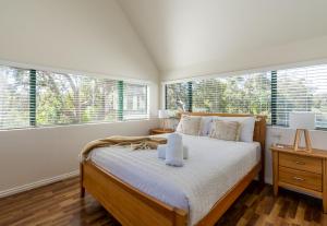 a bedroom with a large bed with white sheets and windows at Casa Rua Margaret River in Witchcliffe