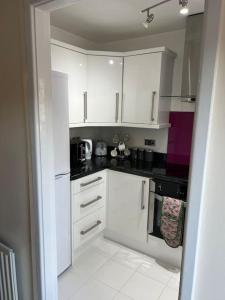 a kitchen with white cabinets and black counter tops at Home Away in Wigan