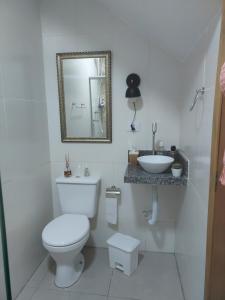 a white bathroom with a toilet and a sink at Casa em São Lourenço-MG in São Lourenço