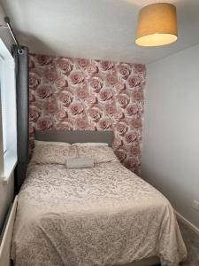 a bedroom with a bed with roses on the wall at Home Away in Wigan