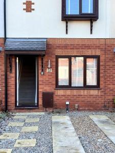 een bakstenen gebouw met een deur en ramen erop bij Home Away in Wigan