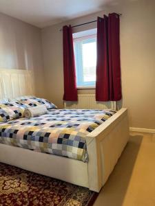 een slaapkamer met een bed en een raam met rode gordijnen bij Home Away in Wigan