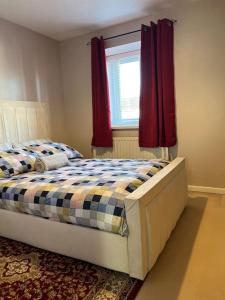 a bedroom with a bed and a window with red curtains at Home Away in Wigan