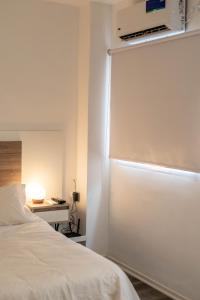 1 dormitorio con cama blanca y puerta corredera en undiano apart en Bahía Blanca