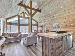 a kitchen and living room in a log cabin at Le Billot- Chalet Rustic avec Spa in Saint-Philémon