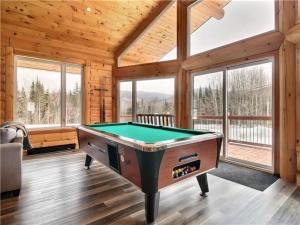 a pool table in a room with windows at Le Billot- Chalet Rustic avec Spa in Saint-Philémon