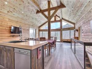 a kitchen and dining room of a log cabin at Le Billot- Chalet Rustic avec Spa in Saint-Philémon