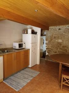 a kitchen with a white refrigerator and a table at Casa do Soito. in Avelãs de Ambom +32 photos