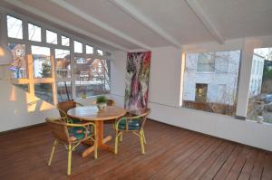 ein Esszimmer mit einem Tisch, Stühlen und Fenstern in der Unterkunft Am Schlosspark - App Seestern in Glücksburg