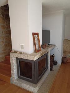 a living room with a stone fireplace with a picture on it at Casa do Soito. in Avelãs de Ambom