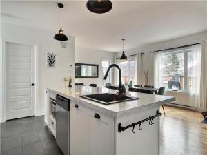 a kitchen with a sink and a counter top at LE FÉÉRIQUE- CHALET AVEC SPA in Saint-Philémon