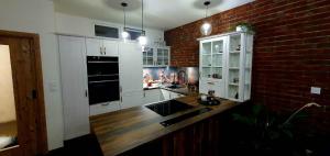 uma cozinha com armários brancos e uma parede de tijolos em Apartmán Jako doma em Olomouc