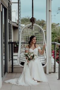 a woman sitting in a white chair holding a bouquet at Currumbin Sanctuary Beach Abode in Gold Coast