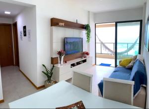 sala de estar con sofá azul y TV en Salvador - Praia do Flamengo - Pé na areia, en Salvador