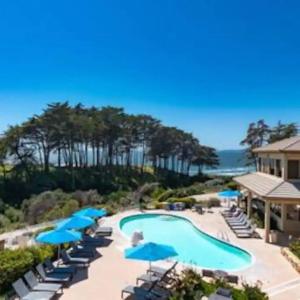 uma piscina com guarda-sóis e cadeiras azuis e o oceano em Beautiful Ocean Views - SEASCAPE - Hot Tubs - Heated Pools - Cozy Fireplace em Aptos