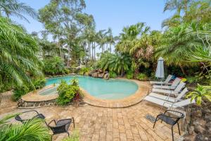 a swimming pool with chairs and a table and an umbrella at Oasis Inn Ulladulla - Welcoming Guests 18 Years and Older in Ulladulla +65 photos