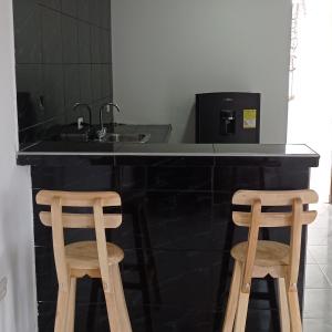 uma cozinha com um lavatório e 2 bancos de madeira em Hostal-Mirador La Popa em Cartagena de Indias