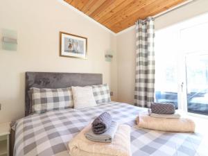 a bedroom with a bed with checked sheets and a window at Brightwater Lodge in Windermere