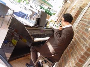 un homme assis devant un piano dans l'établissement Hotel Bedburger Mühle, à Bedburg