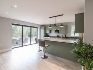 a kitchen with green cabinets and a counter with a chair at Fron Haul - Robin Goch in Ruthin