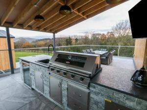 an outdoor kitchen with a grill and a patio at Fron Haul - Robin Goch in Ruthin