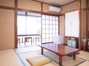 Habitación con mesa y cocina con ventanas. en Harukaze no Yado, en Iwaki