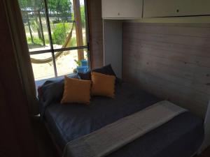 uma cama com duas almofadas num quarto com uma janela em Glass em Punta Del Diablo