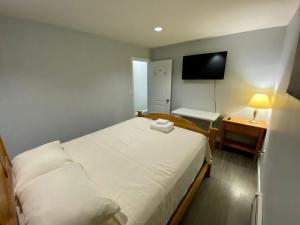 a small bedroom with a white bed and a television at Anne's BNB in Surrey