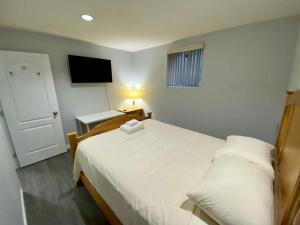 Schlafzimmer mit einem weißen Bett und einem TV in der Unterkunft Anne's BNB in Surrey