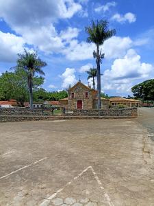 an empty parking lot with palm trees and a church at D'Santos Hospedaria. Aconchego perto de Tiradentes in Coroas