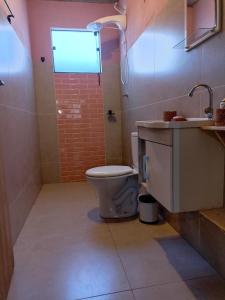 a bathroom with a toilet and a sink and a window at D'Santos Hospedaria. Aconchego perto de Tiradentes in Coroas