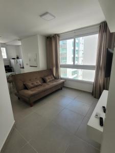 a living room with a couch and a large window at Lindo apartamento 1 quarto in Capão da Canoa