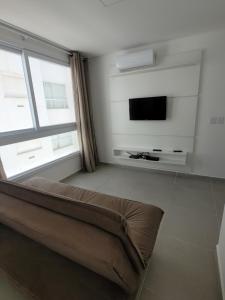 uma sala de estar com um sofá e uma televisão de ecrã plano em Lindo apartamento 1 quarto em Capão da Canoa
