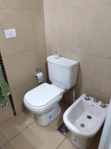 La salle de bains est pourvue de toilettes blanches et d'un lavabo. dans l'établissement Crespo Suites, à Rosario