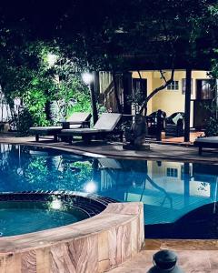 a swimming pool at night with two lounge chairs next to it at Pavillon Indochine Boutique - Hotel in Siem Reap