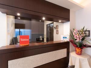 a reception desk with a vase of flowers on a table at Chang Tee Hotel Ikebukuro in Tokyo
