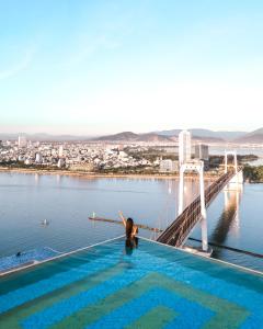 a woman in a swimming pool on a bridge over water at Wyndham Danang Golden Bay in Da Nang