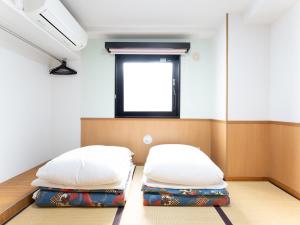 2 camas en una habitación con ventana en Chang Tee Hotel Ikebukuro, en Tokio