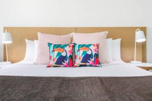 uma cama com duas almofadas coloridas em 'A Perfect Match' Resort-style Living in Darwin CBD em Darwin
